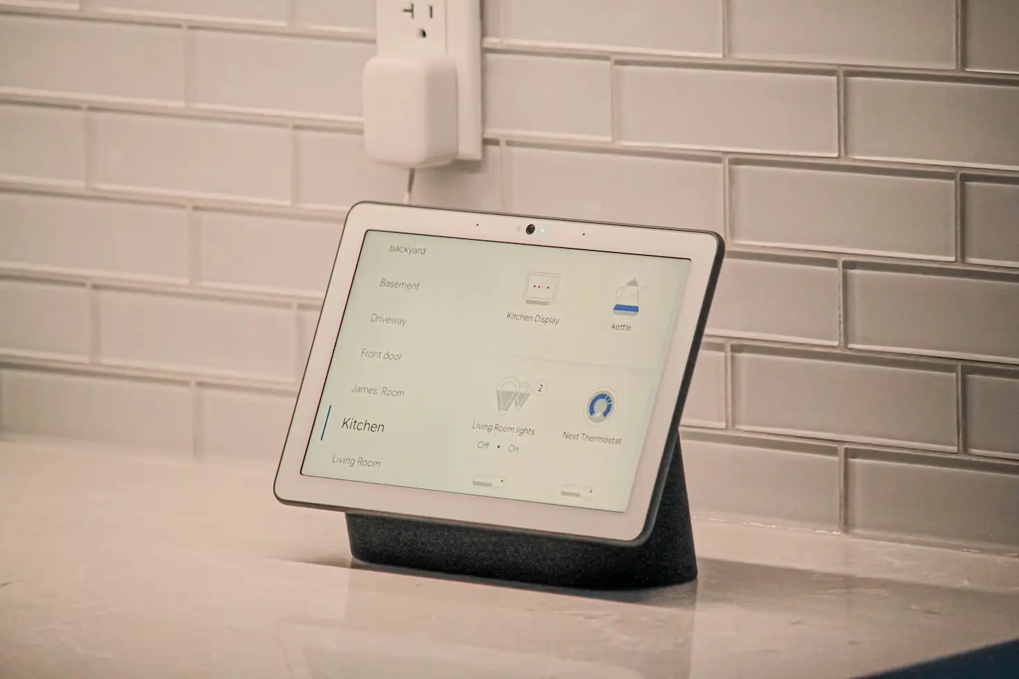 Smart home display on kitchen counter with tiled backsplash and power outlet