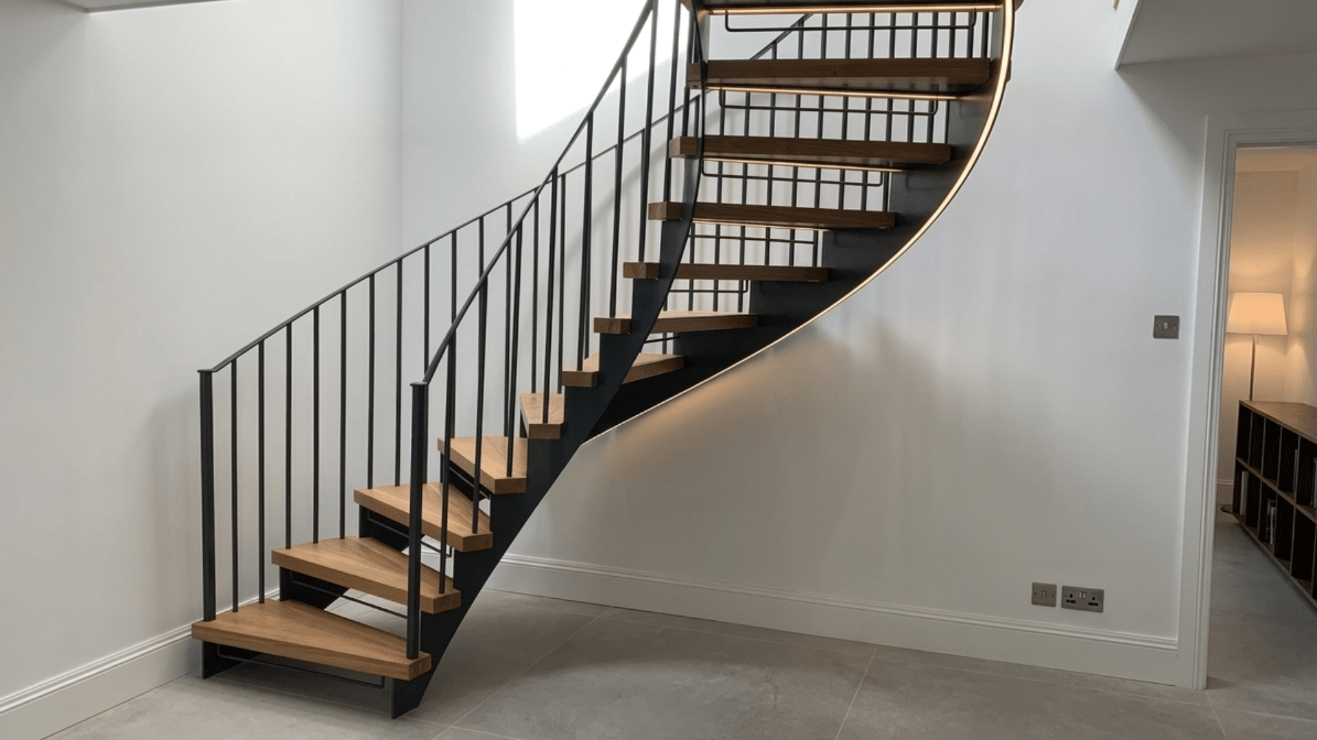 spiral wooden flight of stairs with black metal railing