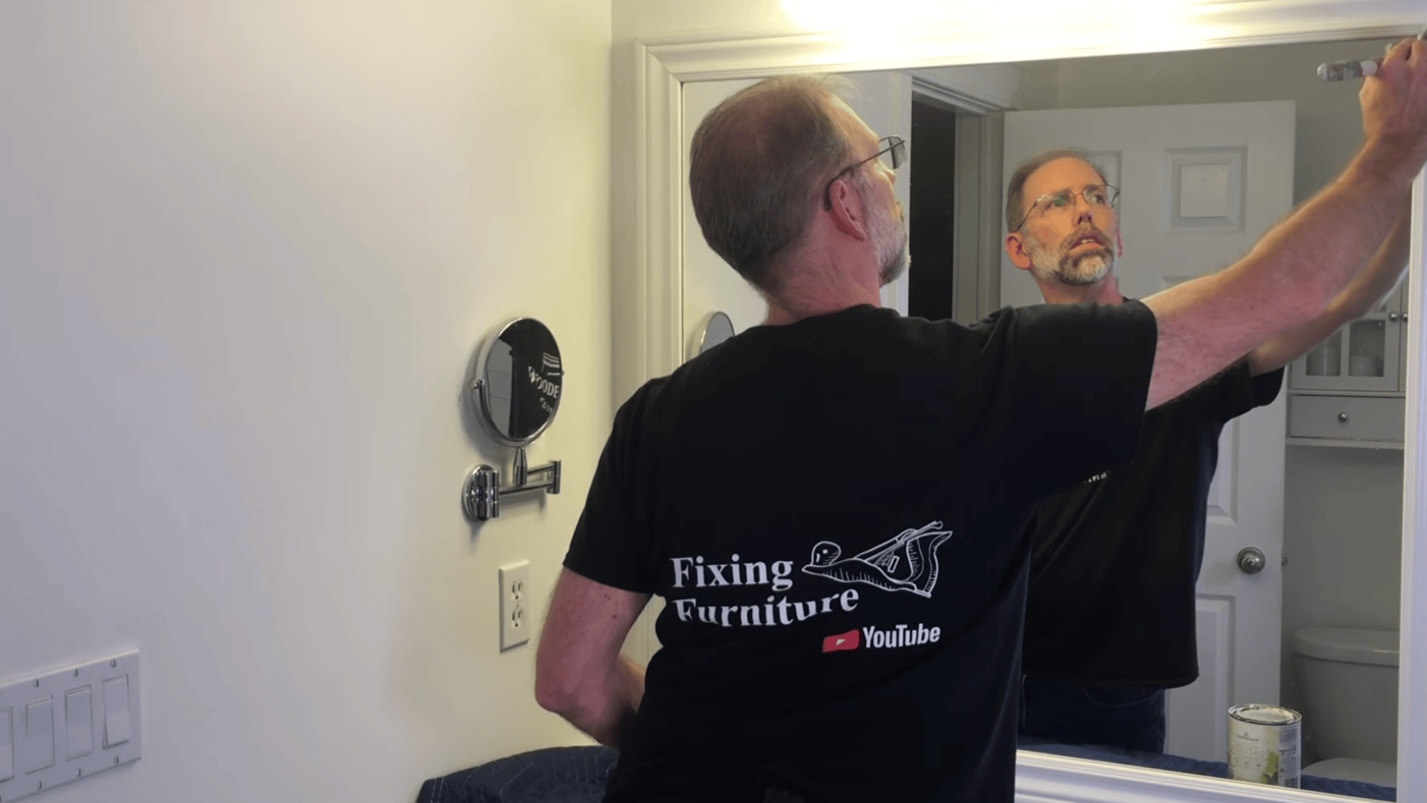 touching up mirror frame corners with paint to hide gaps and create smooth clean finish for final look