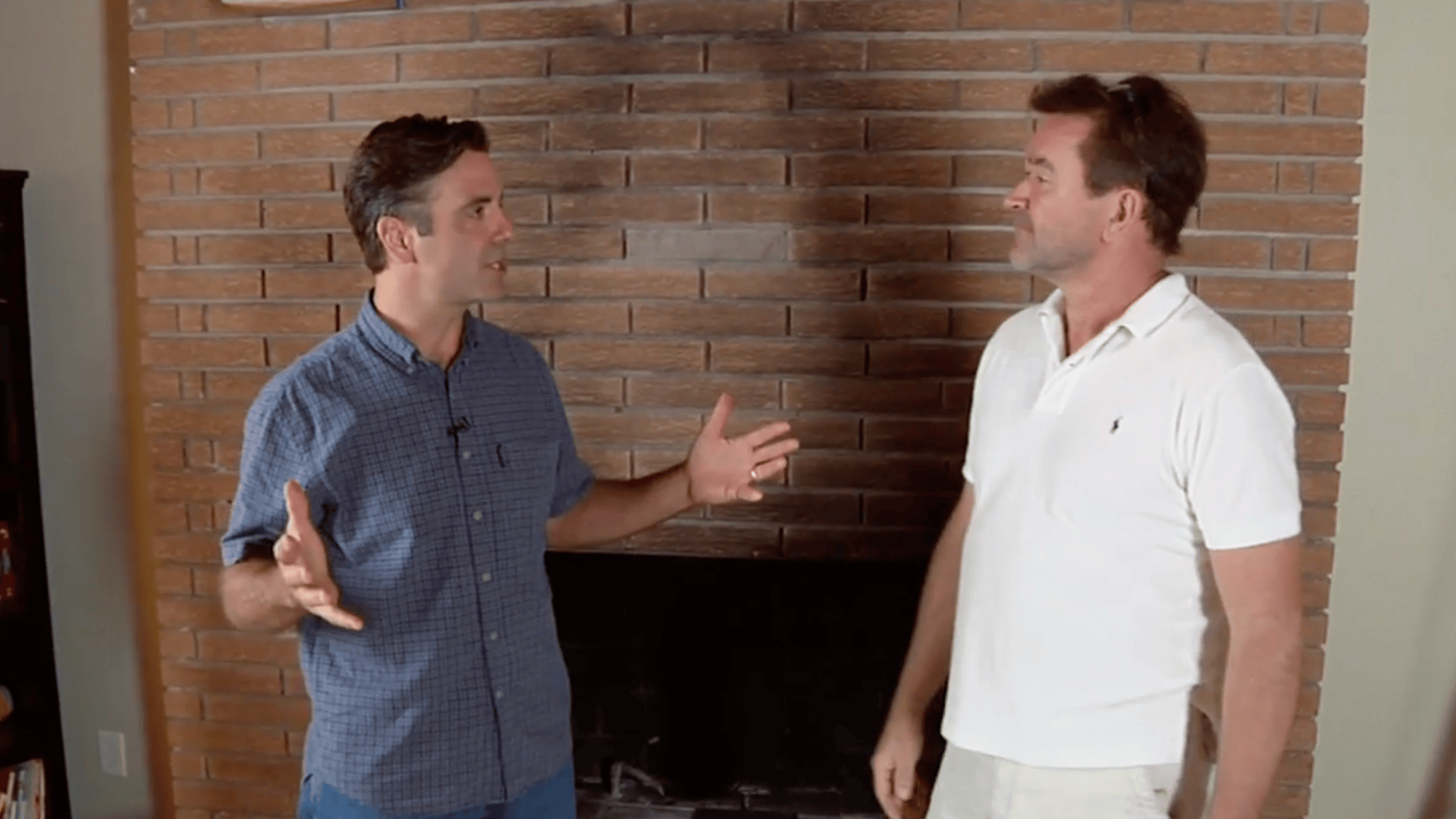 two men discussing plans in front of a brick fireplace to understand the project scope