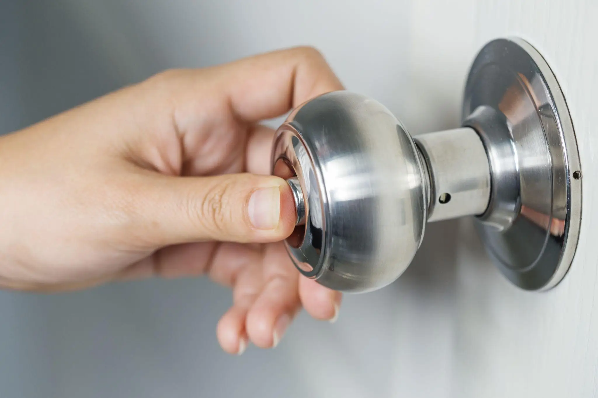 Hand turning a stainless steel door handle in close-up shot