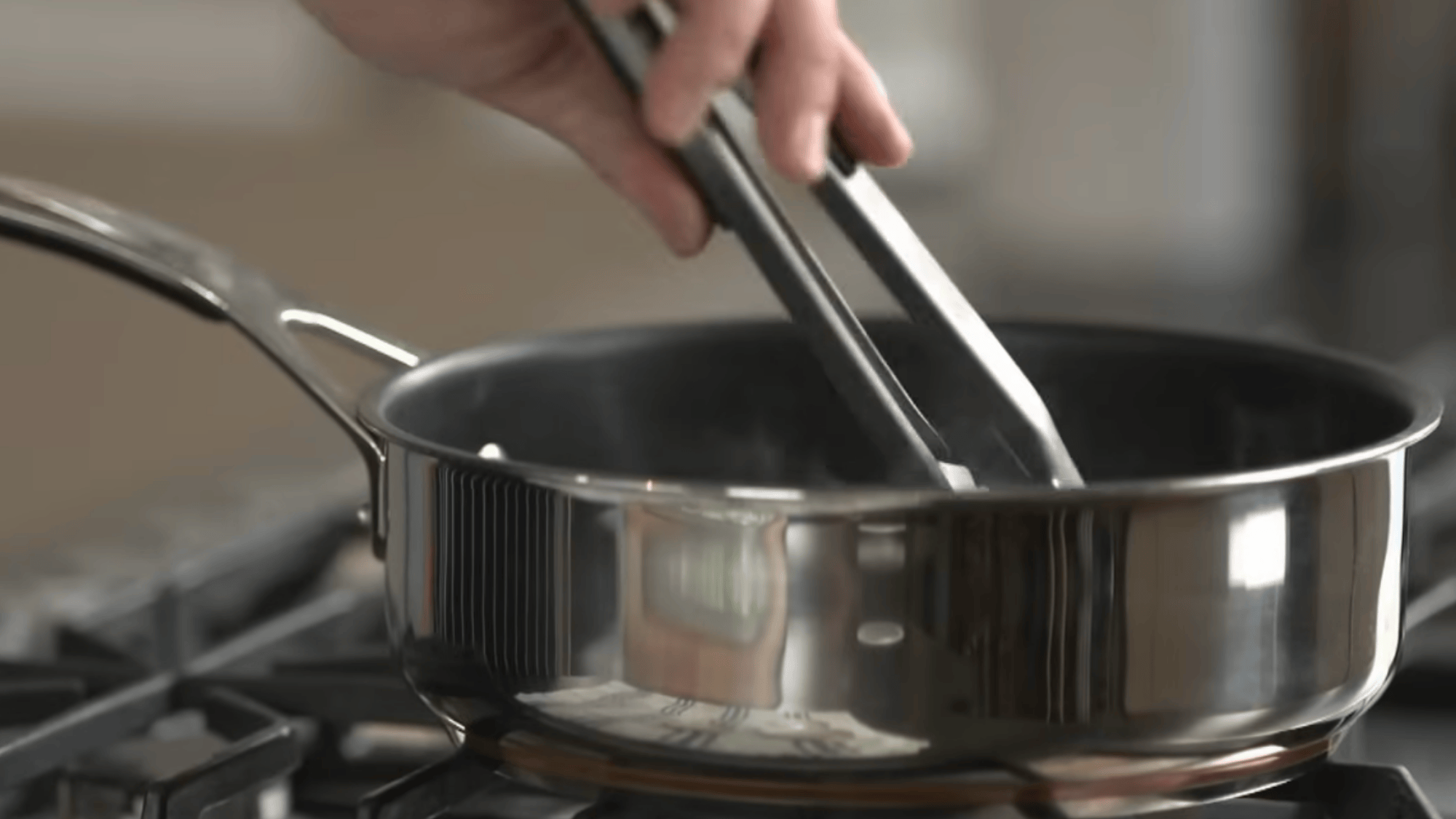 using tongs to lift hot jar lids from water and placing them on clean cloth to dry before sealing jars