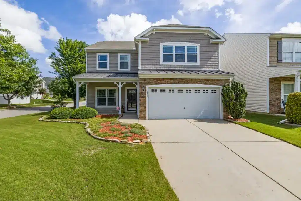 Two-story suburban house with manicured lawn and spacious driveway under clear blue sky