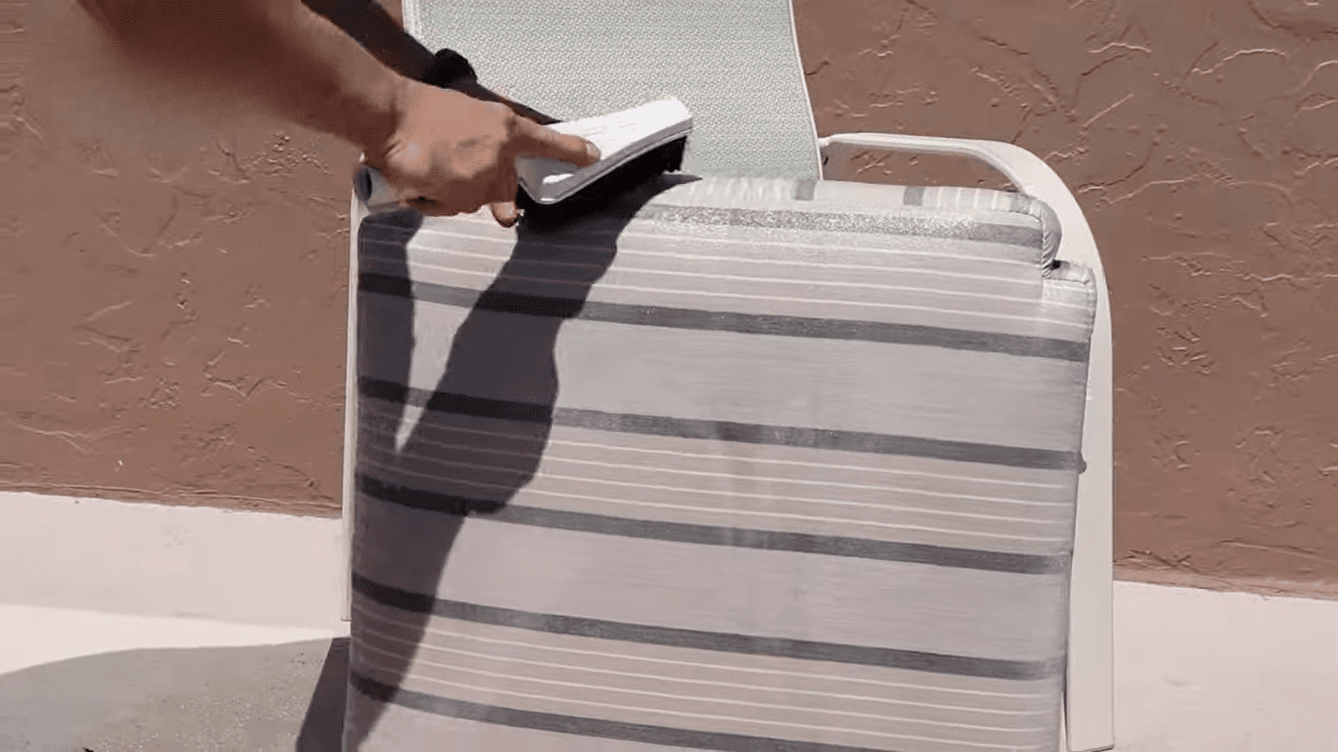 woman scrubbing outdoor cushion with brush and cleaner on patio demonstrating how to clean sunbrella cushions effectively at home