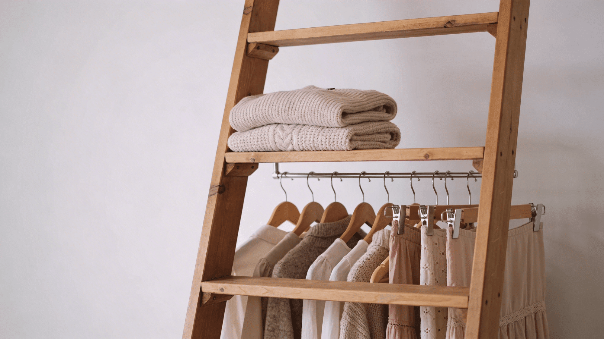 wooden ladder diy clothes rack with hanging clothes and folded sweaters on shelves for storage use