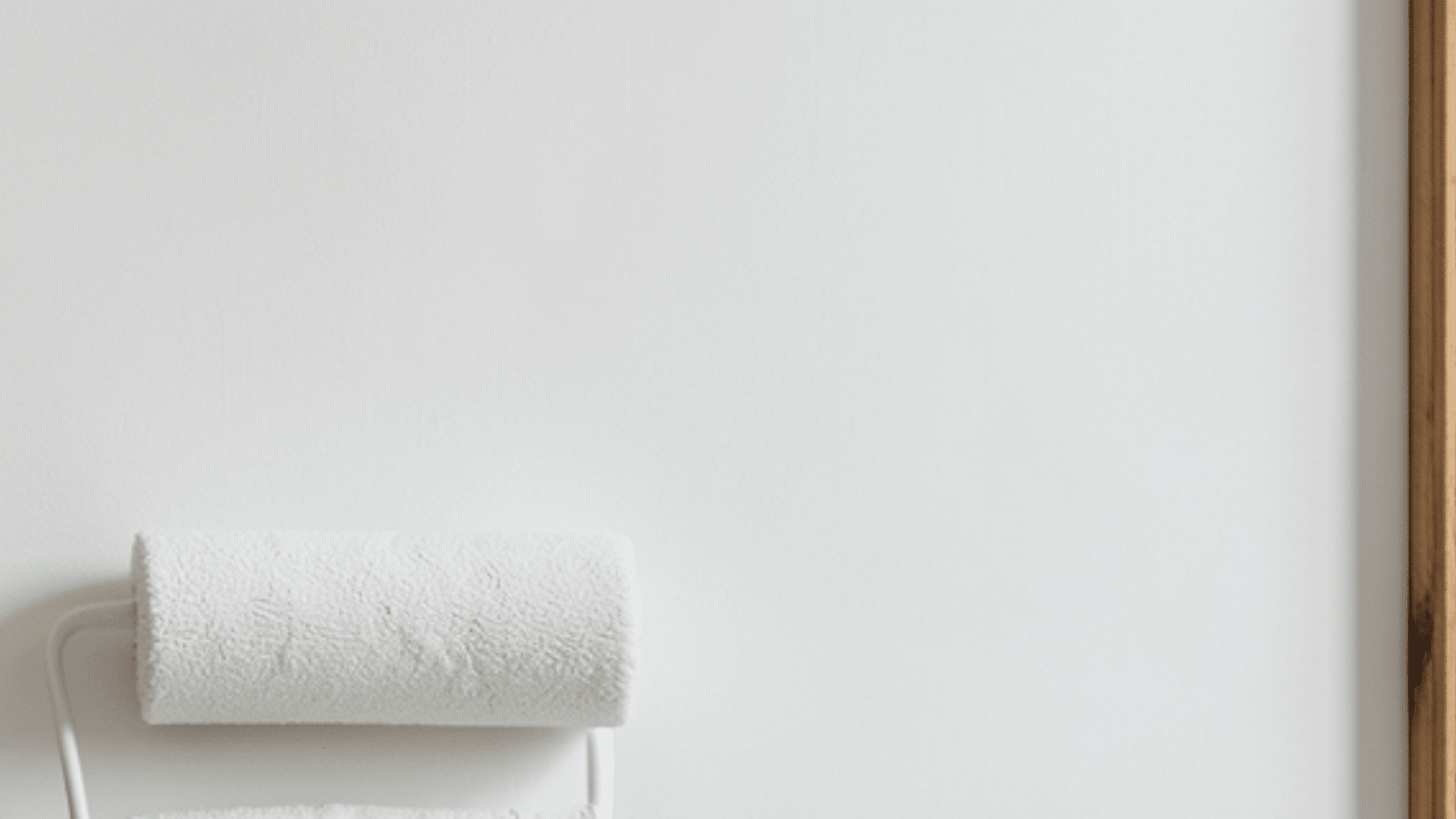 a paint roller on wall with peeling paint beside wooden trim
