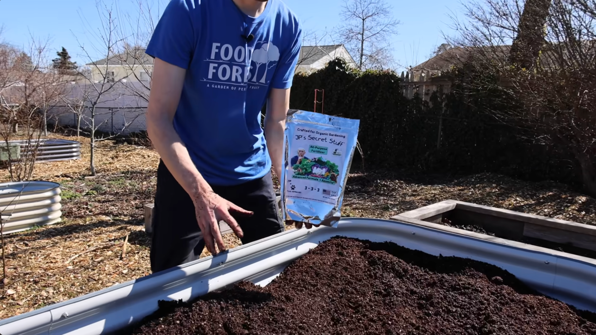 adding fertilizer to finished raised bed showing how to layer a raised garden bed and prepare soil for planting