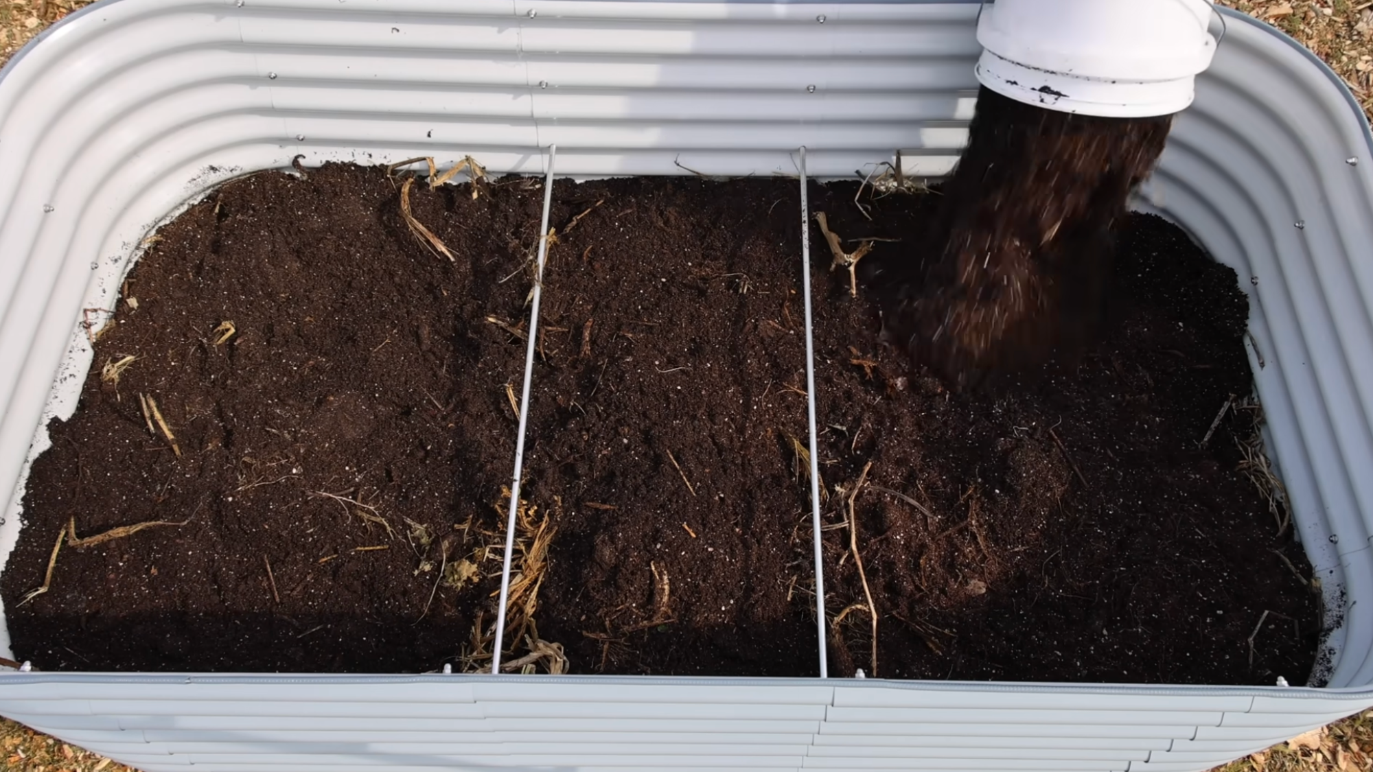 adding topsoil layer in raised bed showing how to layer a raised garden bed for healthy plant growth and nutrient rich soil