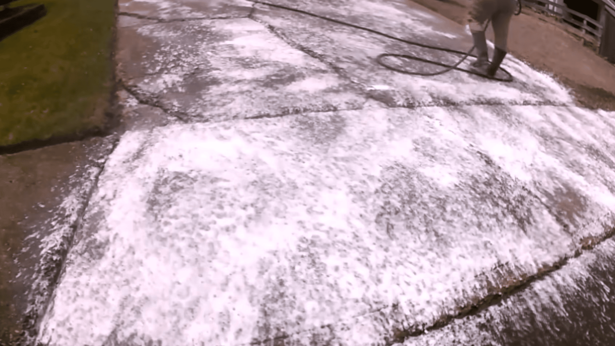 applying cleaner to degrease driveway surface during concrete driveway resurfacing preparation