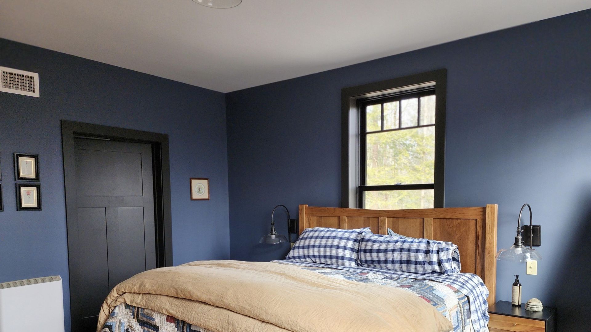 bedroom with blue walls wooden bed with patterned bedding single window wall art and bedside tables with lamps