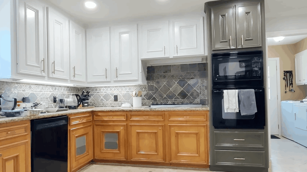 bright kitchen with white upper cabinets wooden lower cabinets tiled backsplash and black oven beside laundry area
