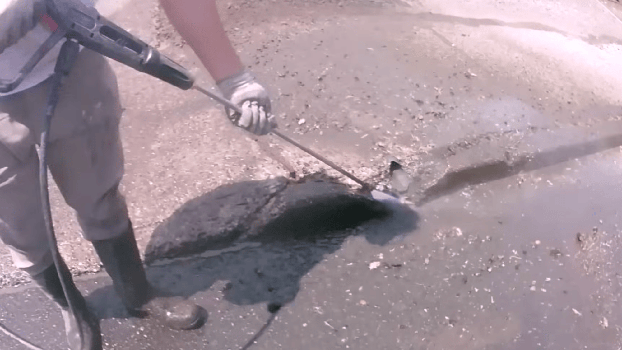 cleaning driveway cracks with pressure washer during concrete driveway resurfacing preparation