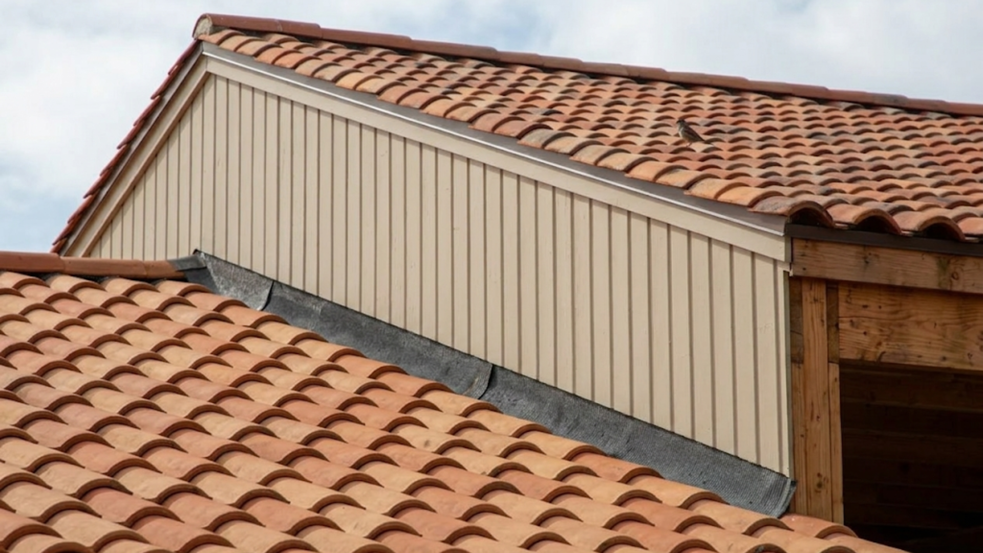 close view of tiled roof valley flashing showing what is flashing on a house where two roof sections meet and seal joints