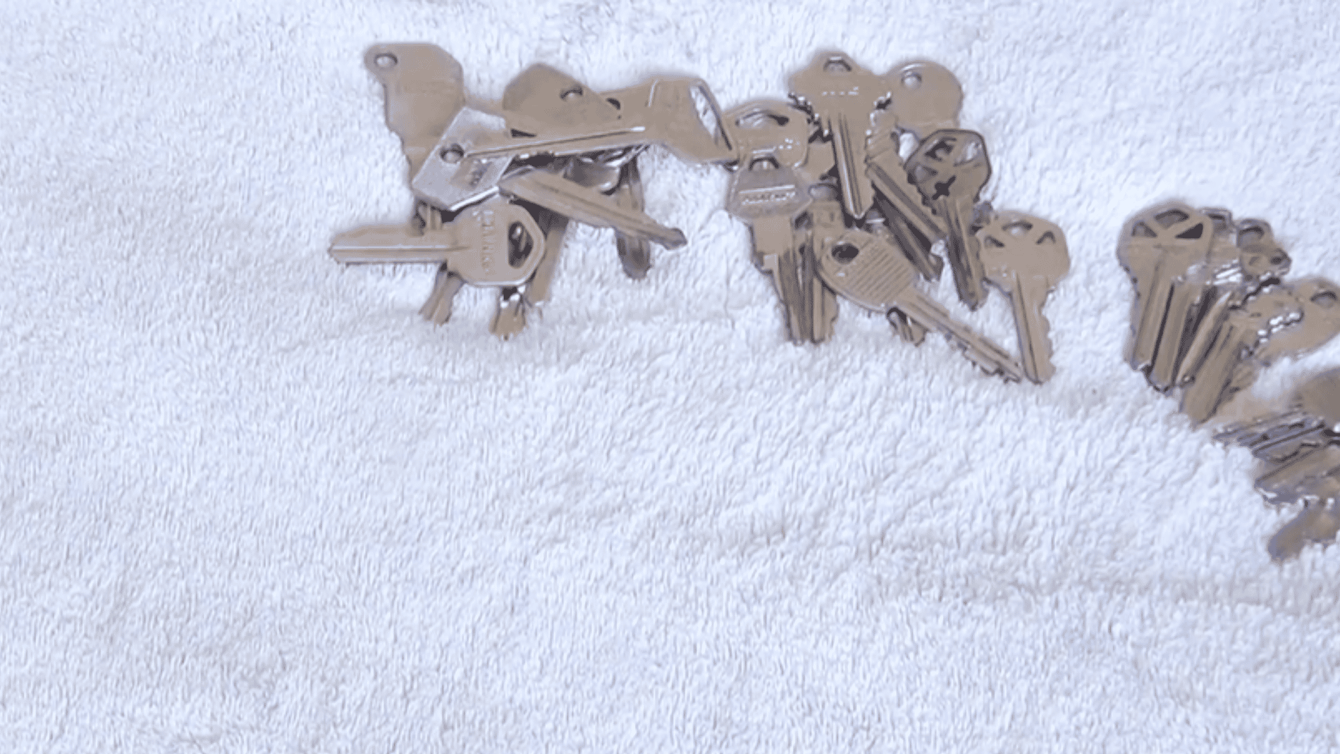 collection of old metal keys sorted by size on a white towel for a diy wind chime craft project