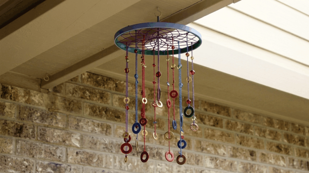 How to Make DIY Key Wind Chimes at Home? colorful diy wind chime hanging under a patio roof with beads rings and strings moving in the breeze