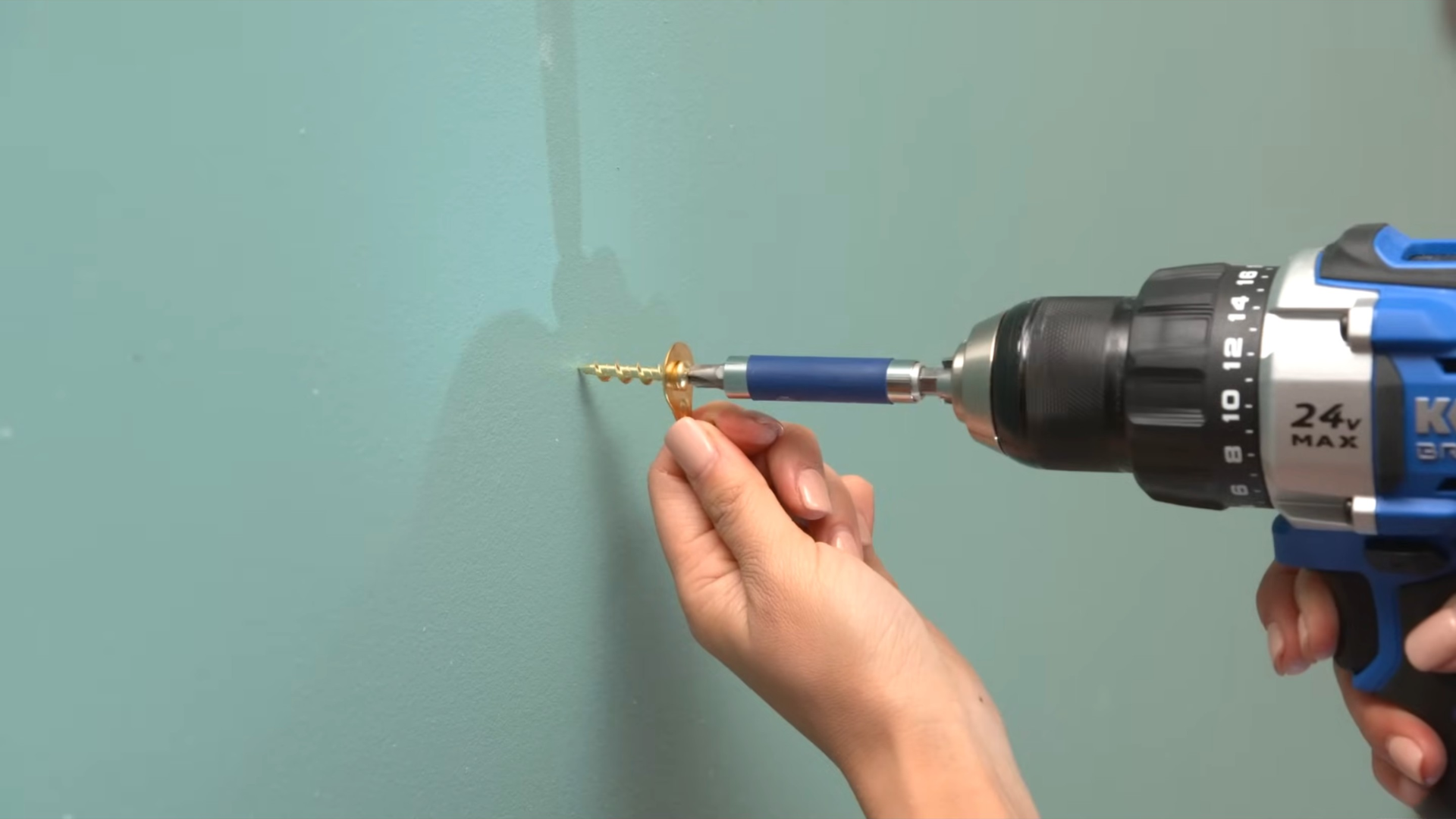 Drilling a screw into a wall using a power drill to install a picture hook