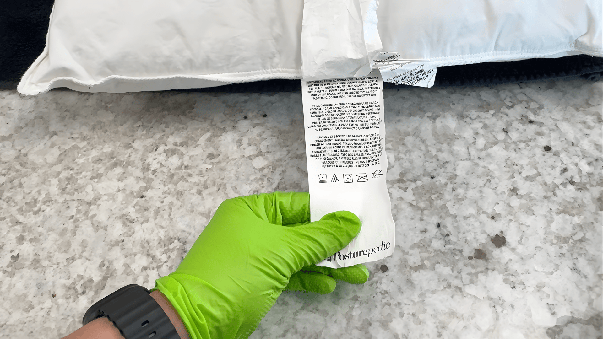 hand wearing green glove holding pillow care label showing instructions how to wash pillows can you wash pillows safely at home