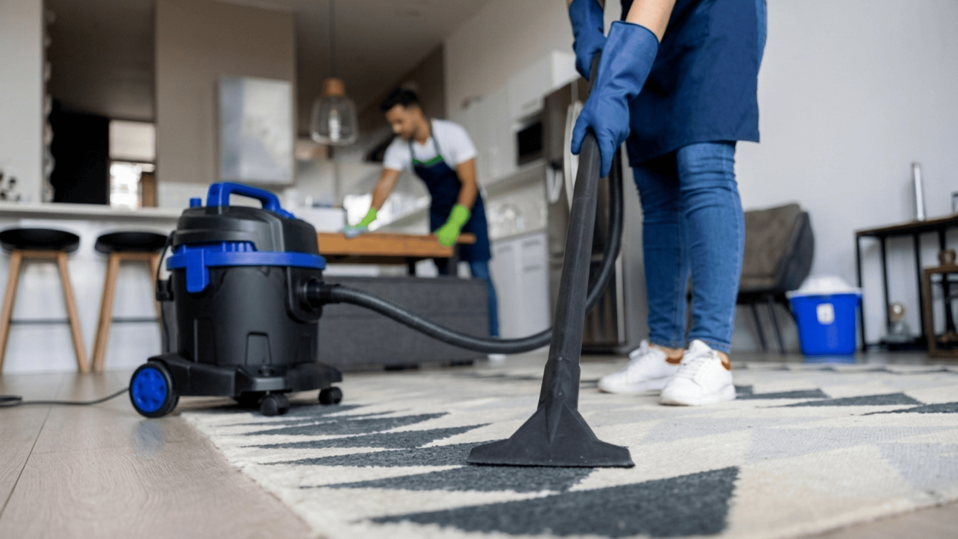 house cleaners vacuuming a rug while another cleans a table in a modern home interior