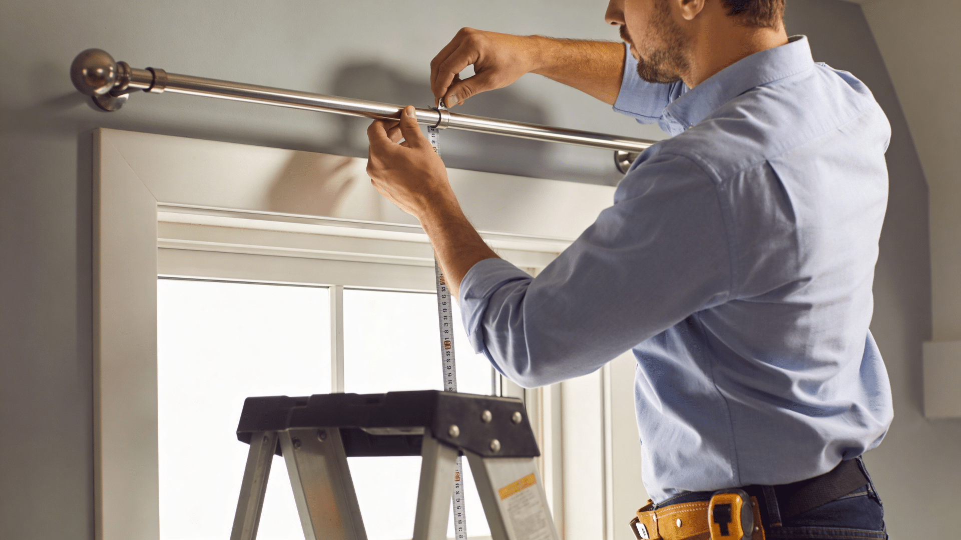 man installing curtain rod height above window