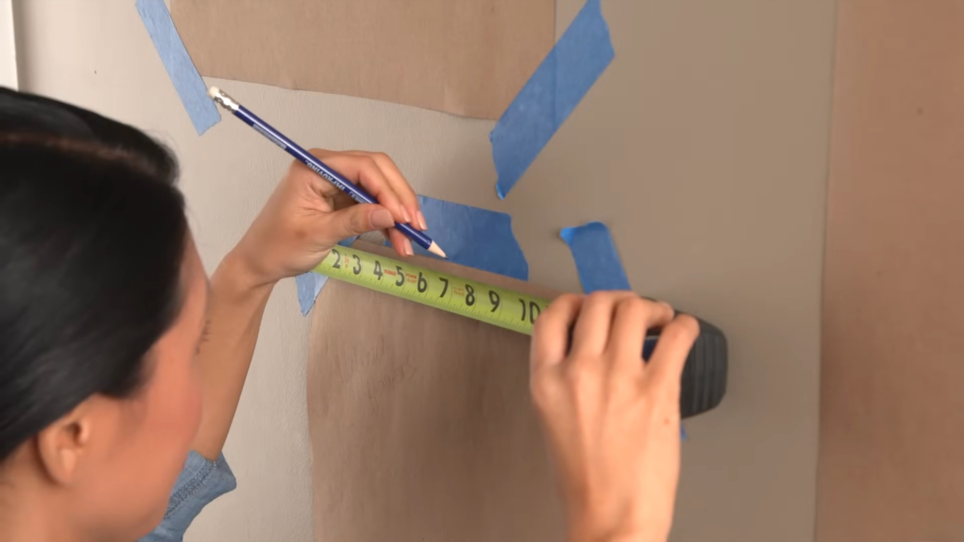 Measuring and marking a wall using a tape measure and pencil for picture placement