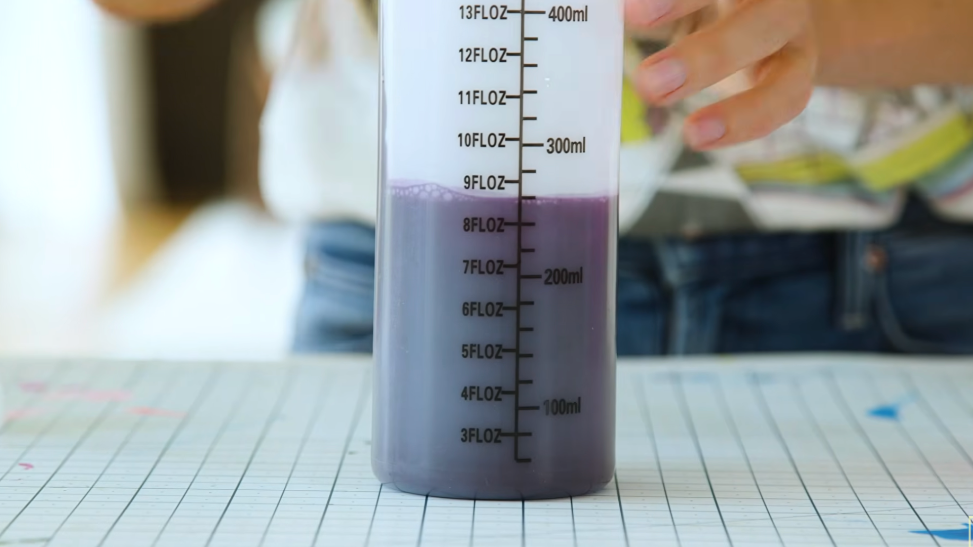 measuring bottle filled with purple dye solution placed on a crafting table during tie dye preparation process