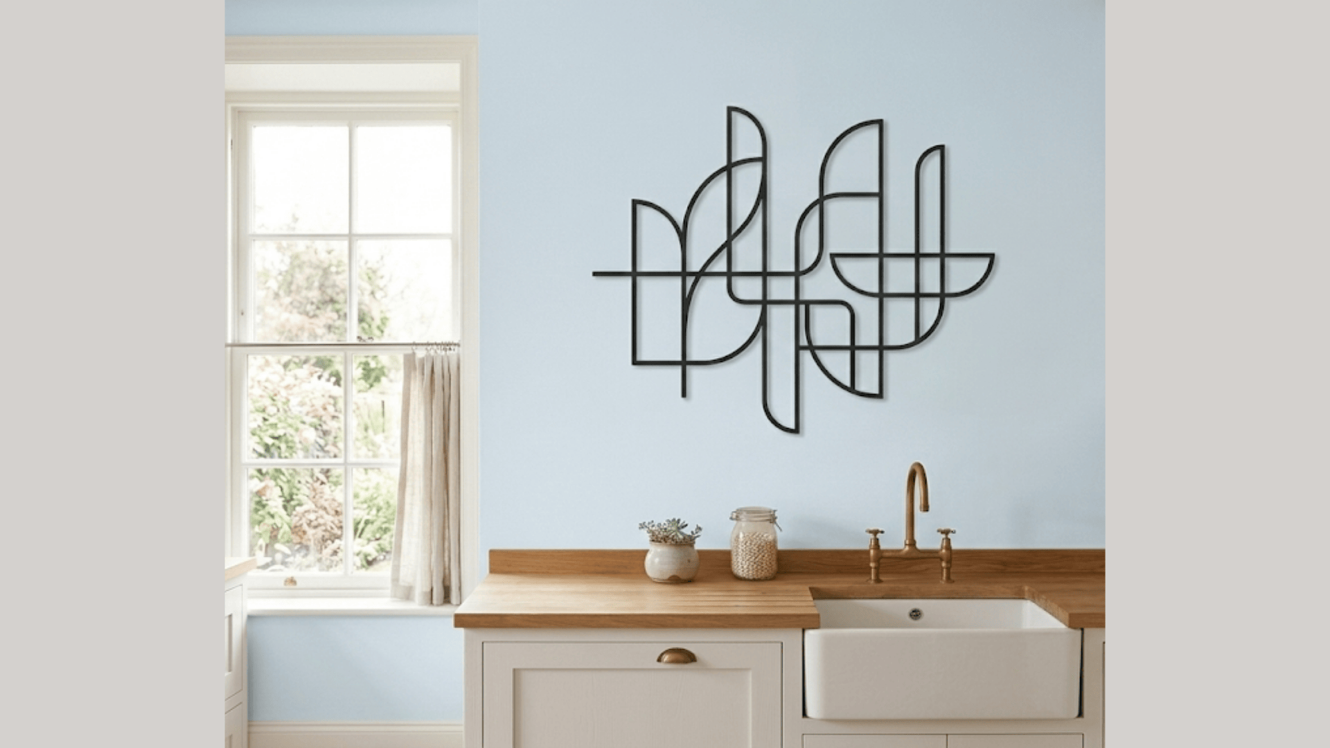 minimalist metal wall decor on light blue kitchen wall above wooden countertop and sink