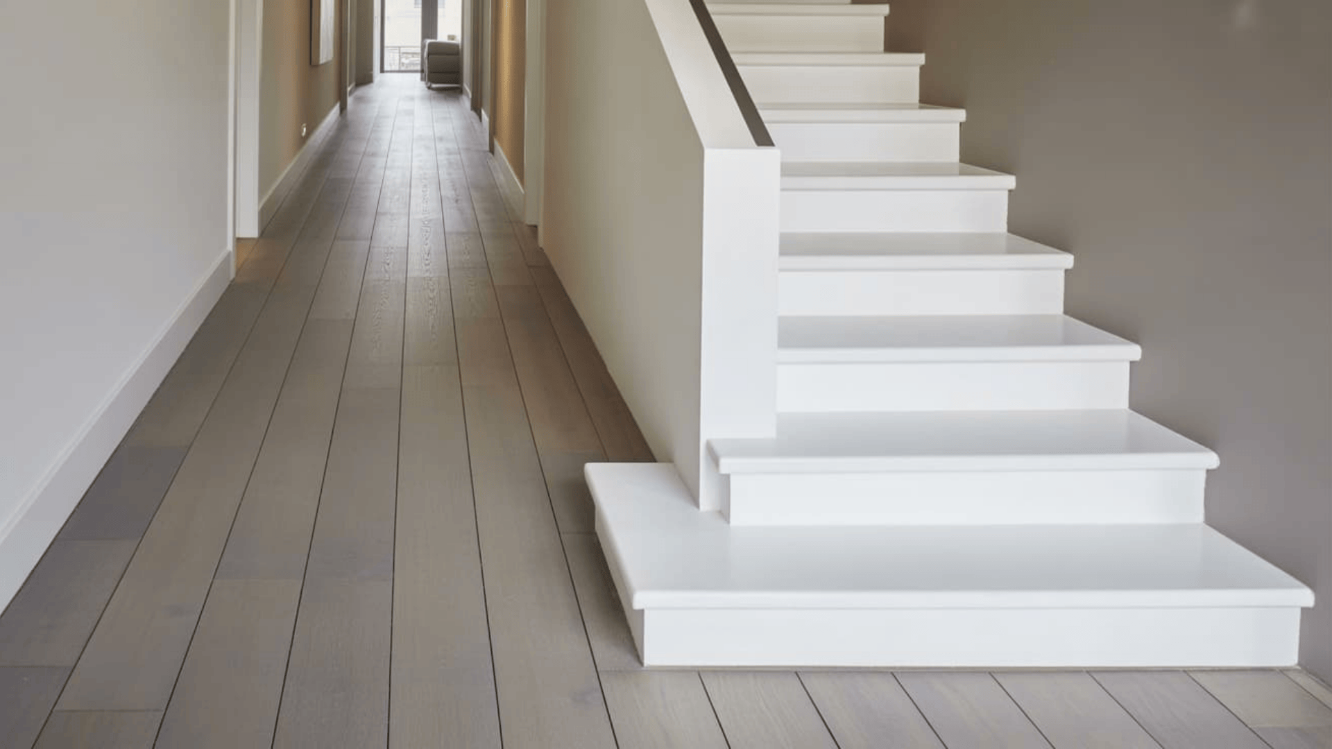 modern hallway with white staircase and gray wood flooring featuring popular hardwood floor stain colors in a minimalist home interior