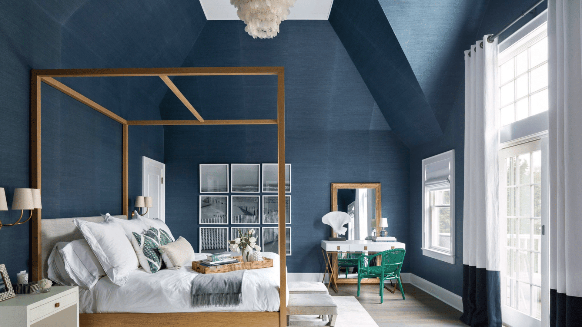Modern navy blue bedroom with canopy bed, white bedding, chandelier, large windows and workspace styled for mens room decor