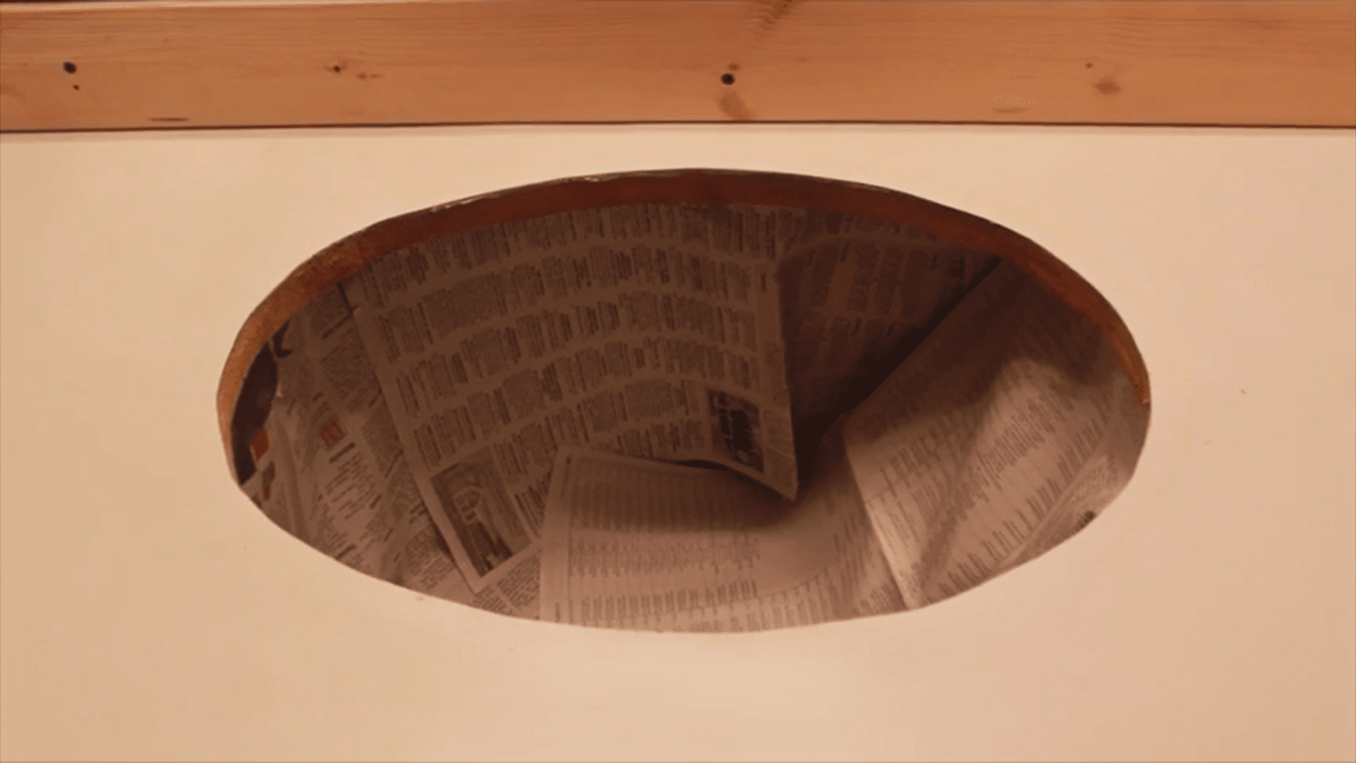 Oval cutout in kitchen surface with newspaper lining inside cabinet for resurfacing laminate countertops
