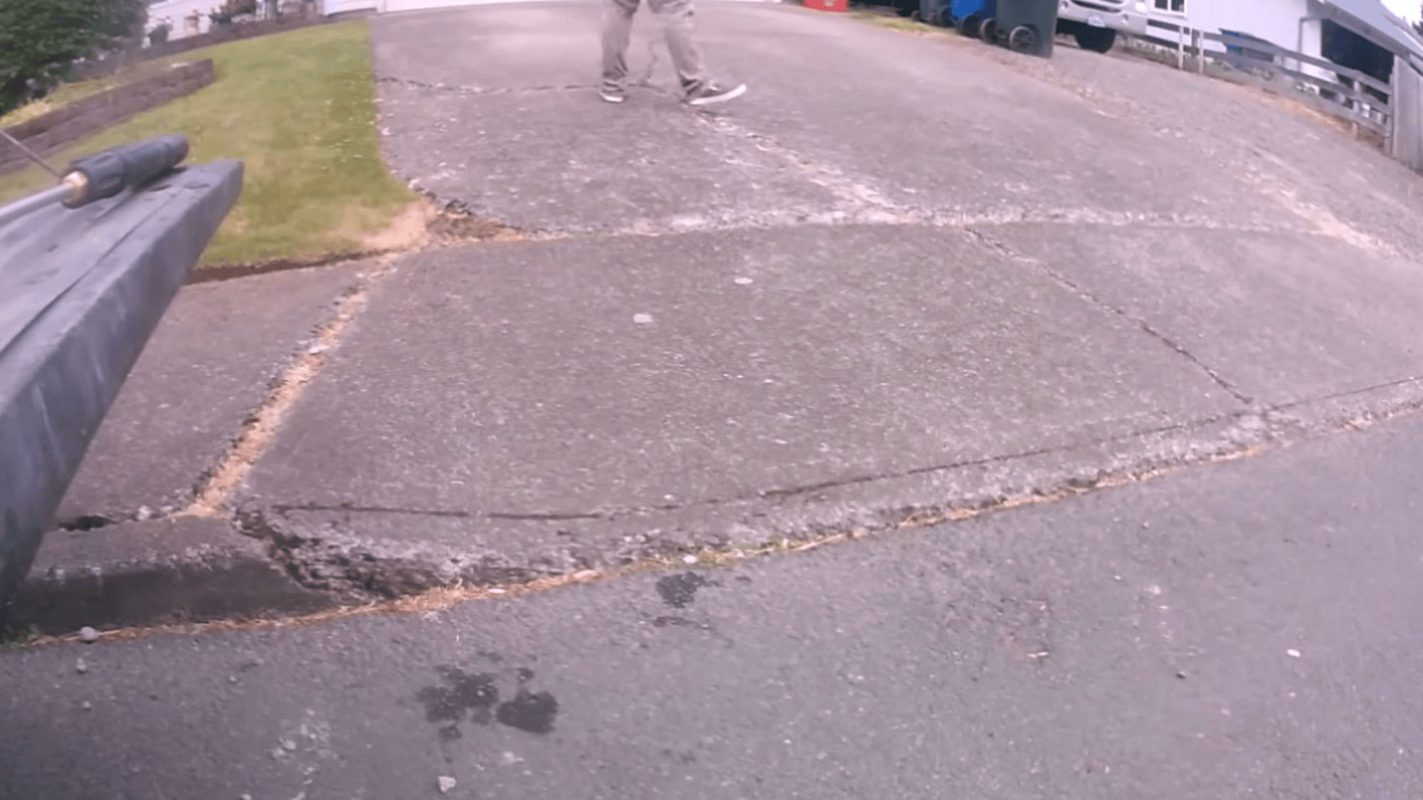 person inspecting cracks and damage on driveway before concrete driveway resurfacing taking photos for repair assessment