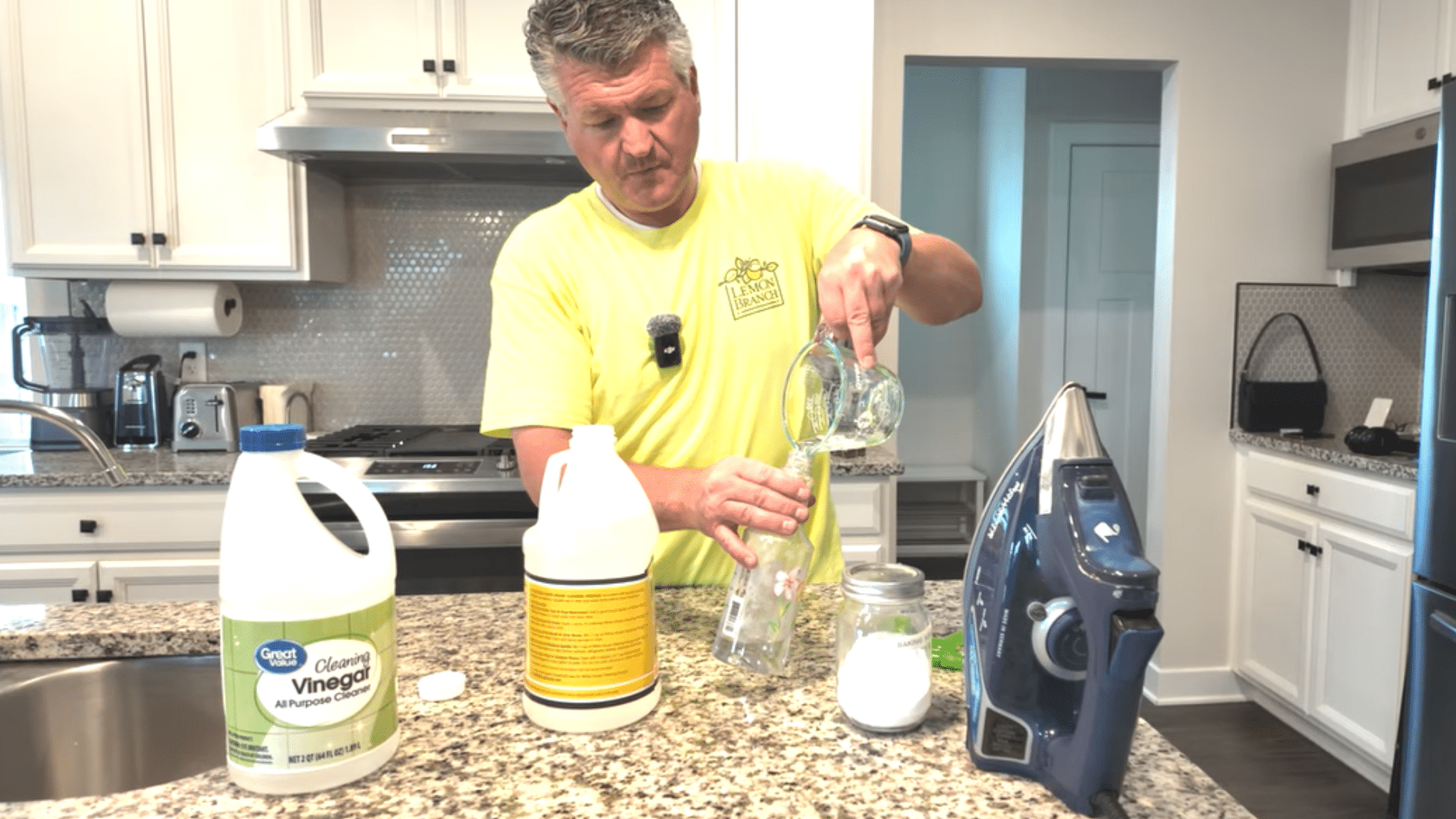 person pouring vinegar into a spray bottle on a kitchen counter with baking soda and an iron nearby