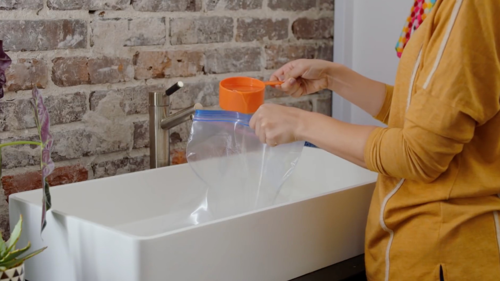person pours cleaning solution into a zip bag near sink to remove hard water stains naturally at home