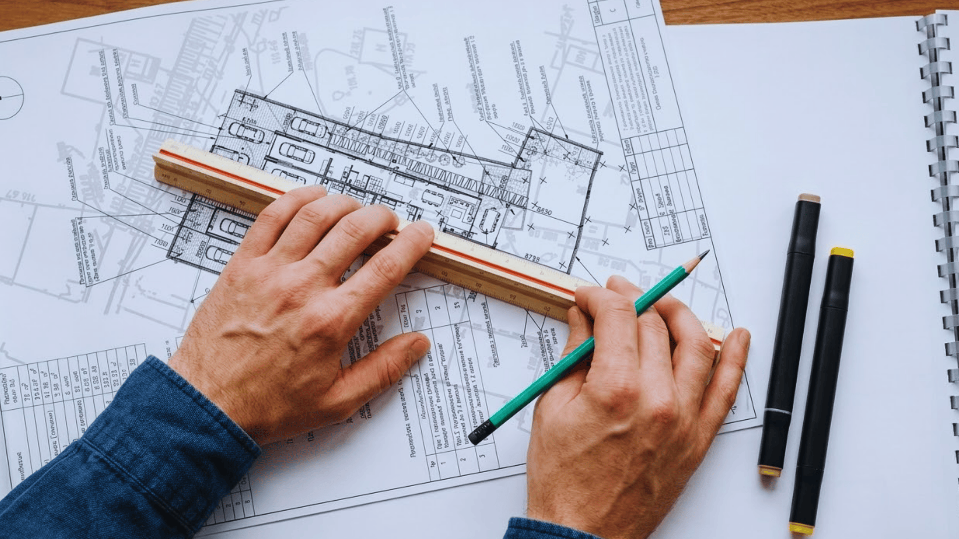 Person using a ruler and pencil on a reflected ceiling plan blueprint on a table