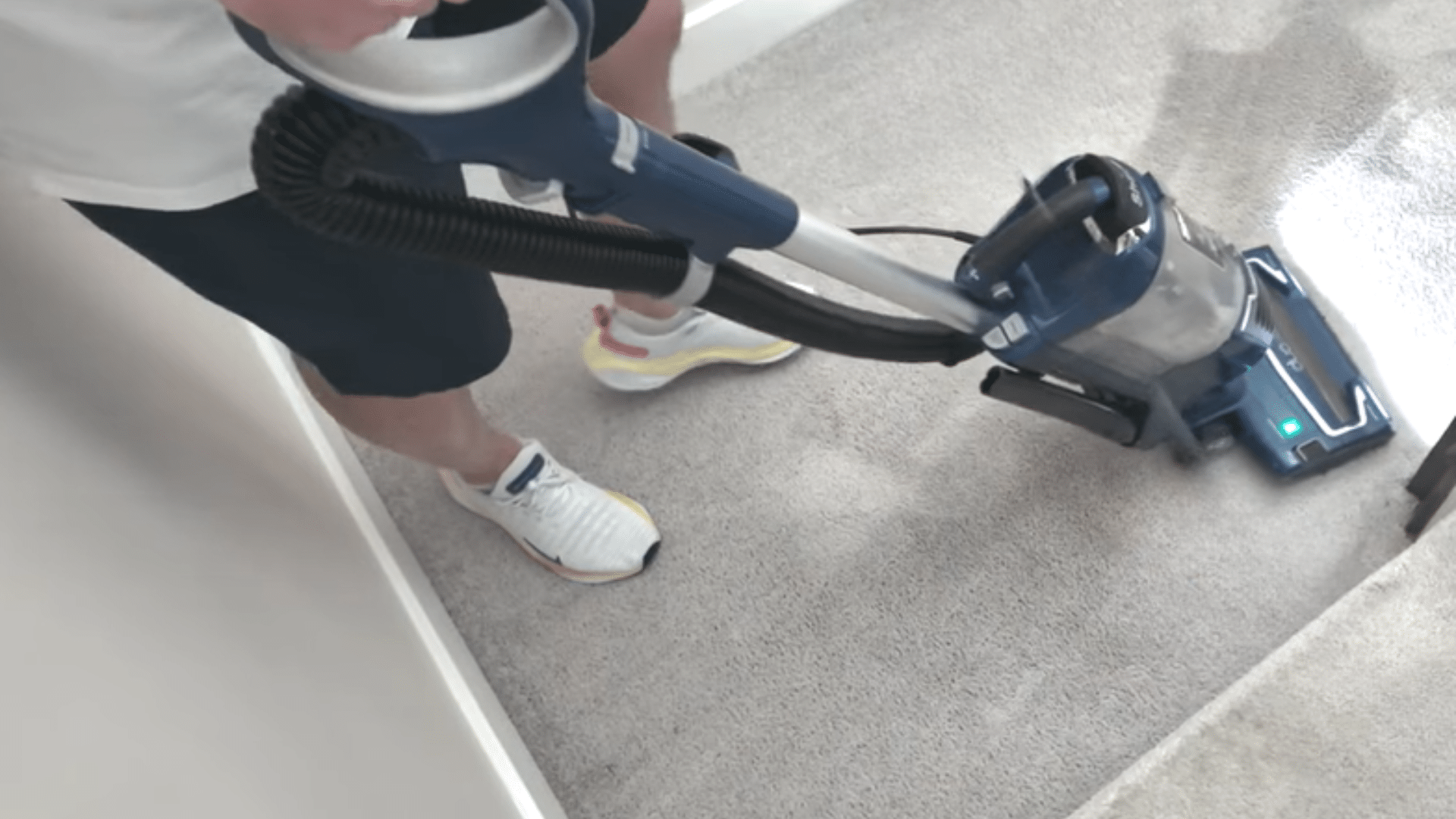 person vacuuming the light grey carpet again after cleaning to refresh the pile and finish the process