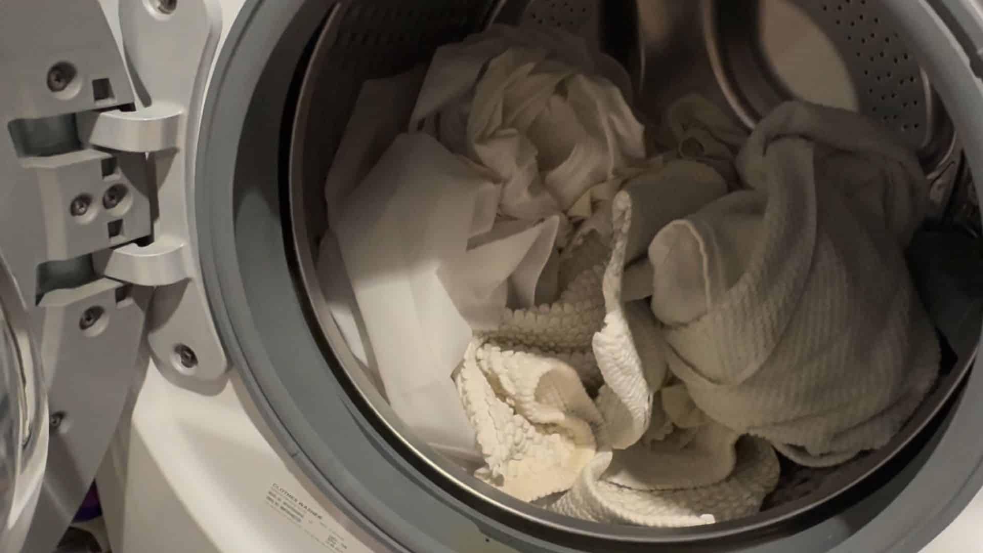 place shower curtain and liner evenly inside washing machine along with a few towels to help scrub away dirt during the wash