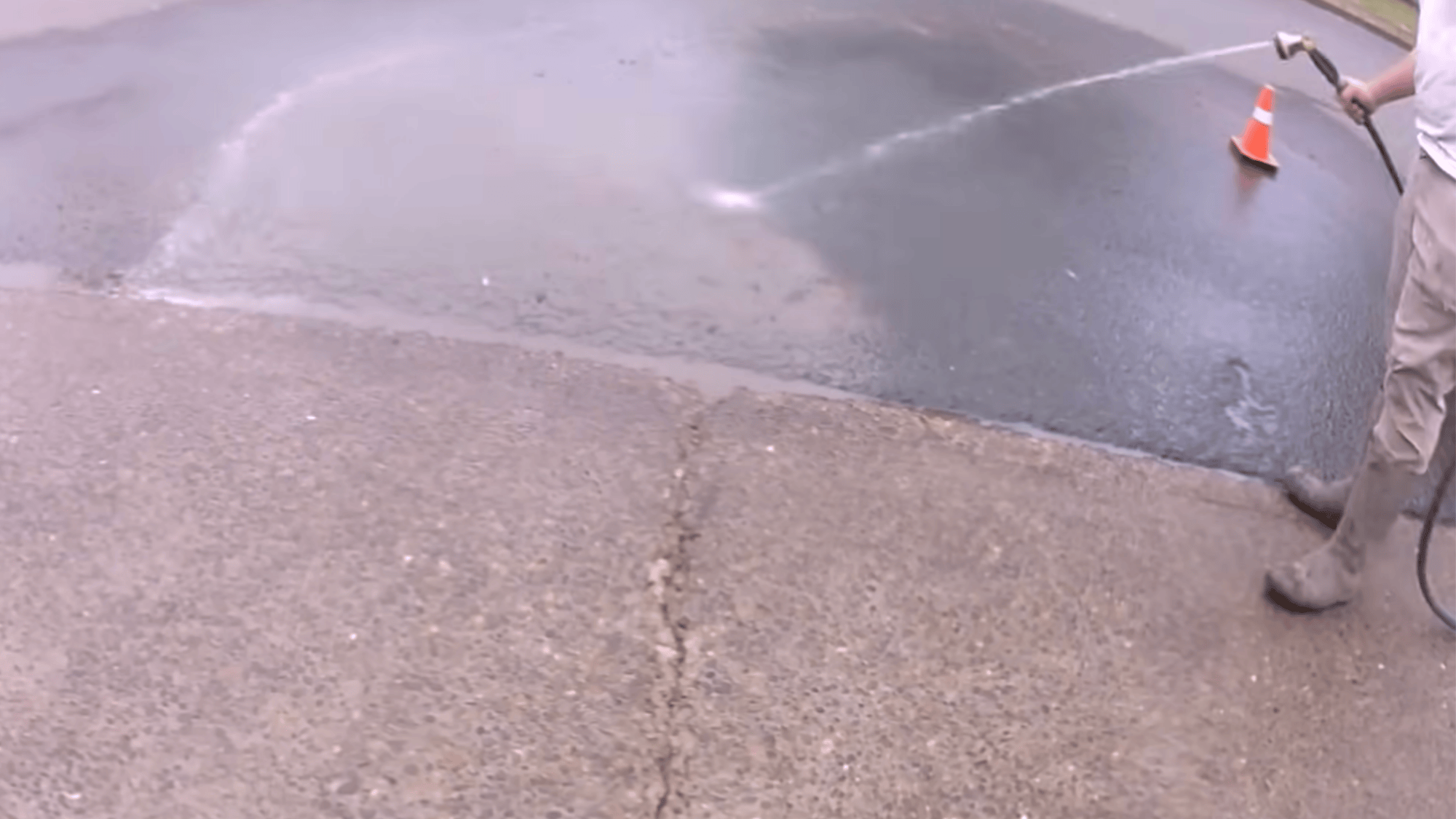rinsing driveway surface with water during concrete driveway resurfacing preparation