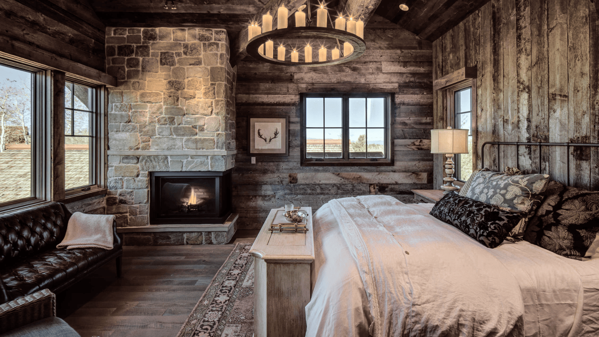 Rustic wooden cabin bedroom with stone fireplace, chandelier, wooden walls and cozy bed creating warm mens room decor style