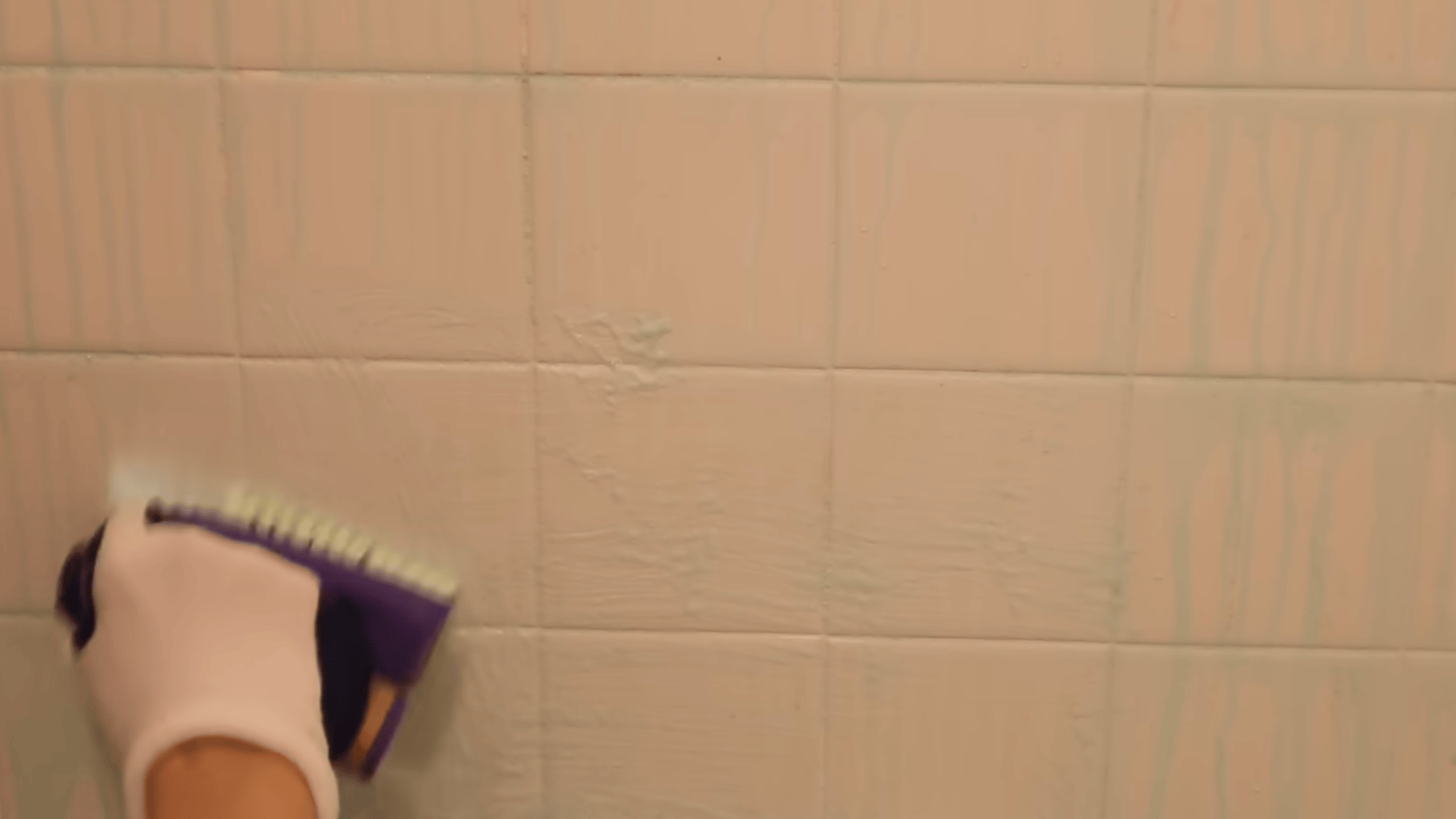 scrubbing shower tiles with firm brush to remove mold