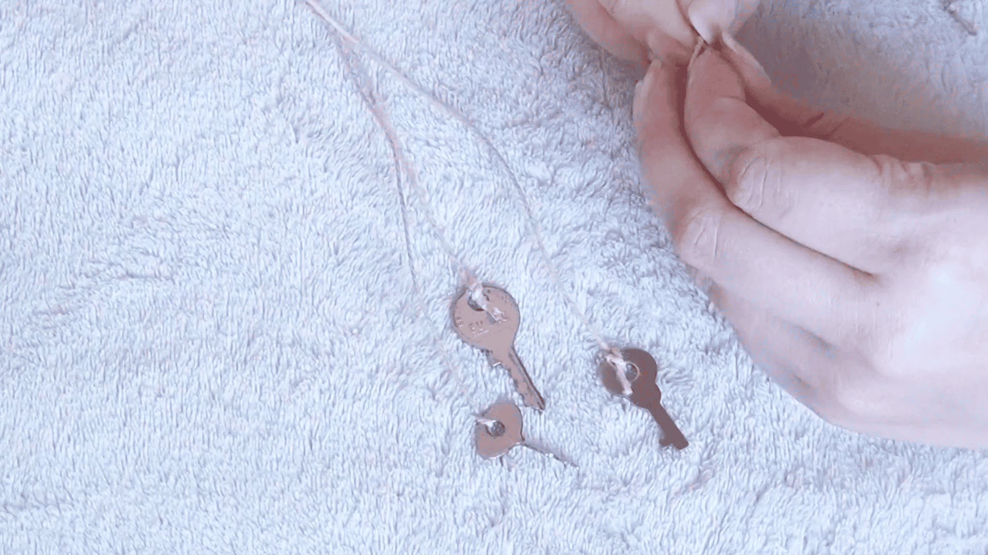 small metal keys tied onto hemp string while making hanging strands for a diy wind chime craft project