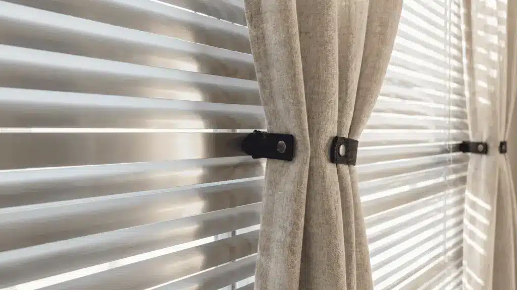 Lightweight curtains held in place on metal blinds using magnetic ties.