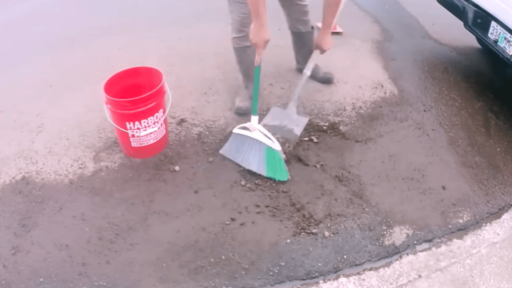 sweeping debris and rinsing driveway surface during concrete driveway resurfacing preparation