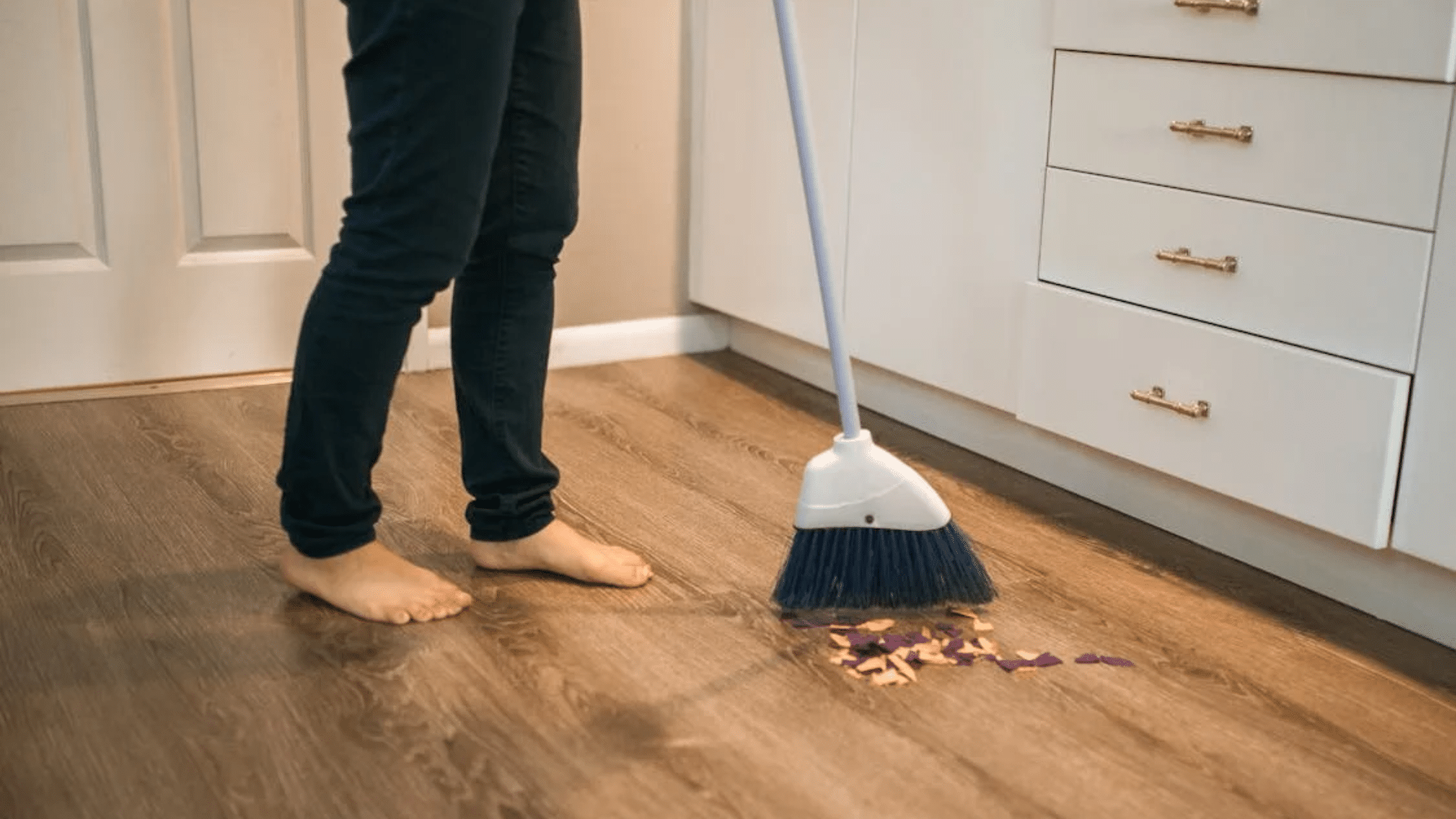 sweeping kitchen floor as part of daily house cleaning routine