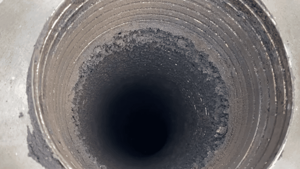 top-down view of chimney flue with heavy soot and creosote buildup along inner walls dark opening below
