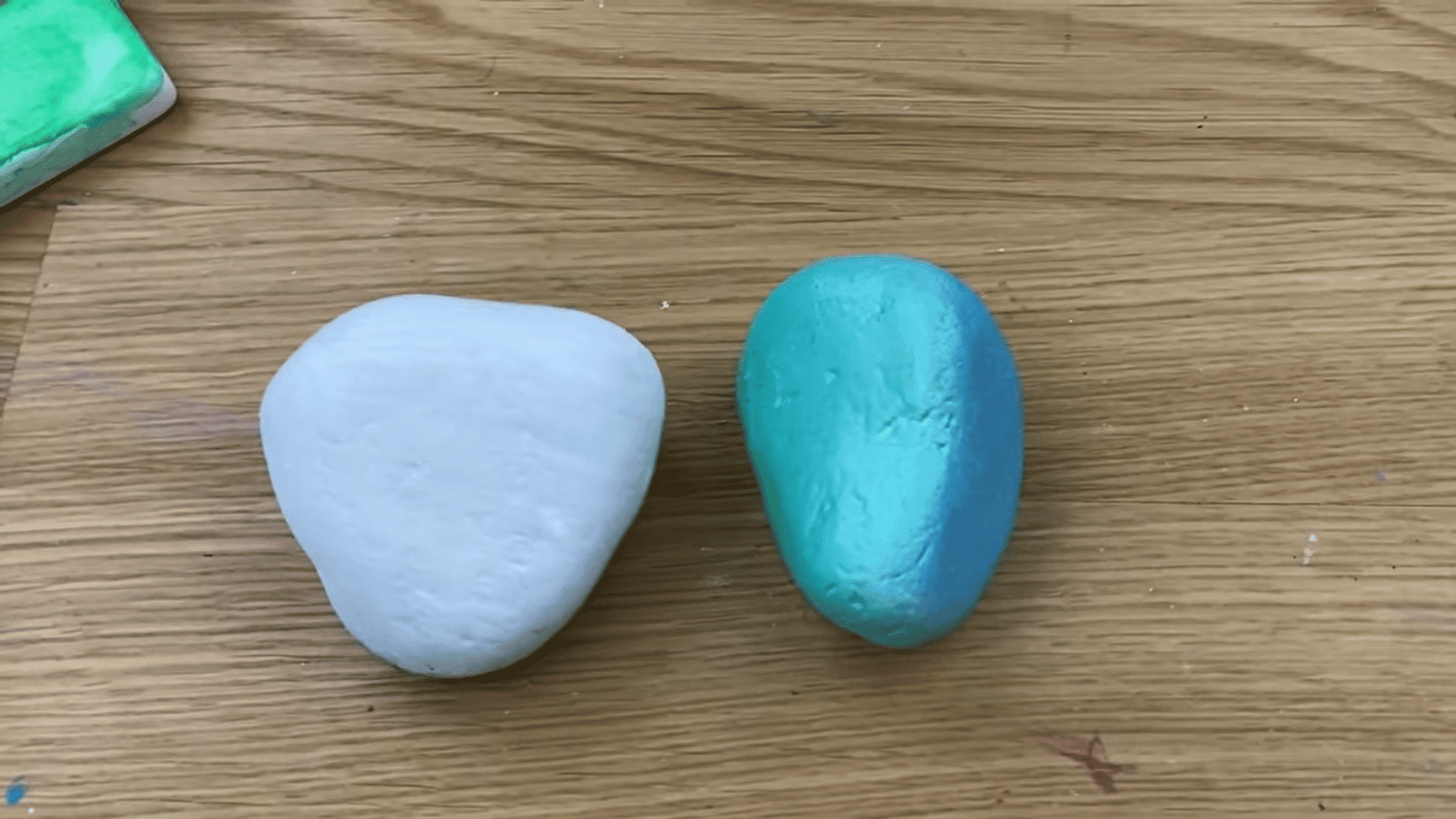 two painted rocks with white and blue base coats placed on wooden table ready for rock painting designs