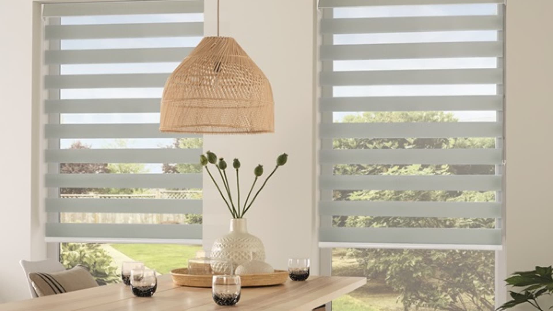 types of window coverings shown as modern zebra blinds with alternating sheer and solid fabric panels over bright dining room windows letting in soft light