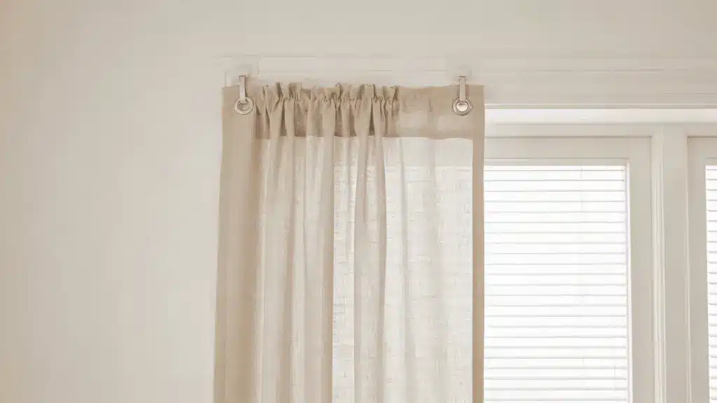 Lightweight curtains hanging on adhesive hooks over window blinds