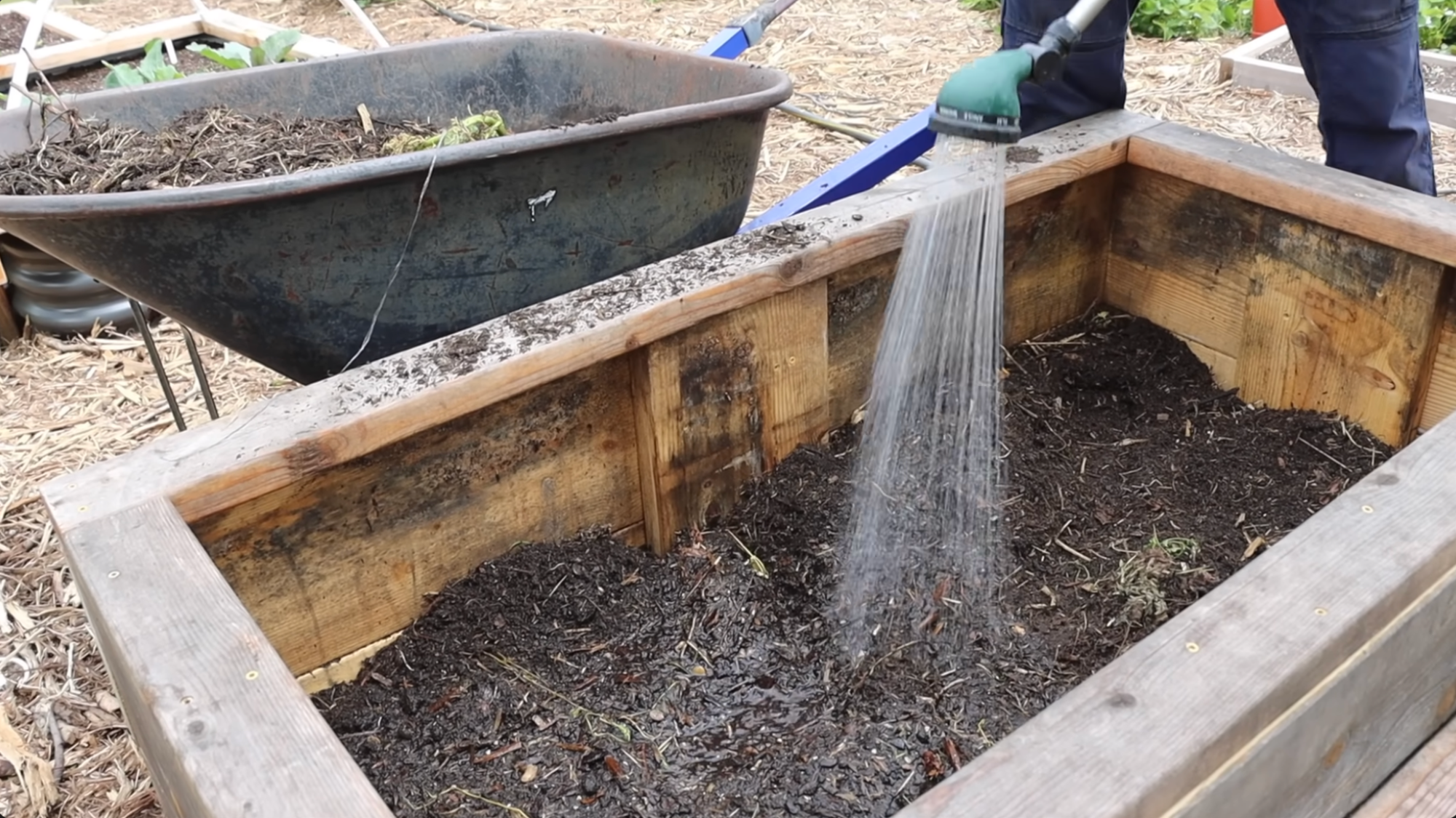 watering raised garden bed after layering showing how to layer a raised garden bed and help soil settle evenly