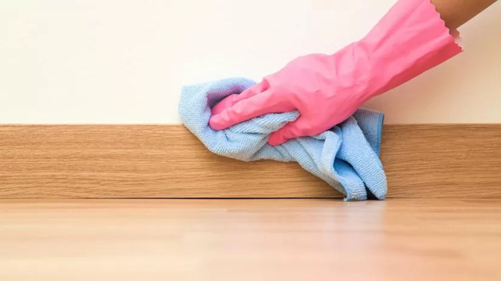 wiping baseboards during monthly house cleaning routine