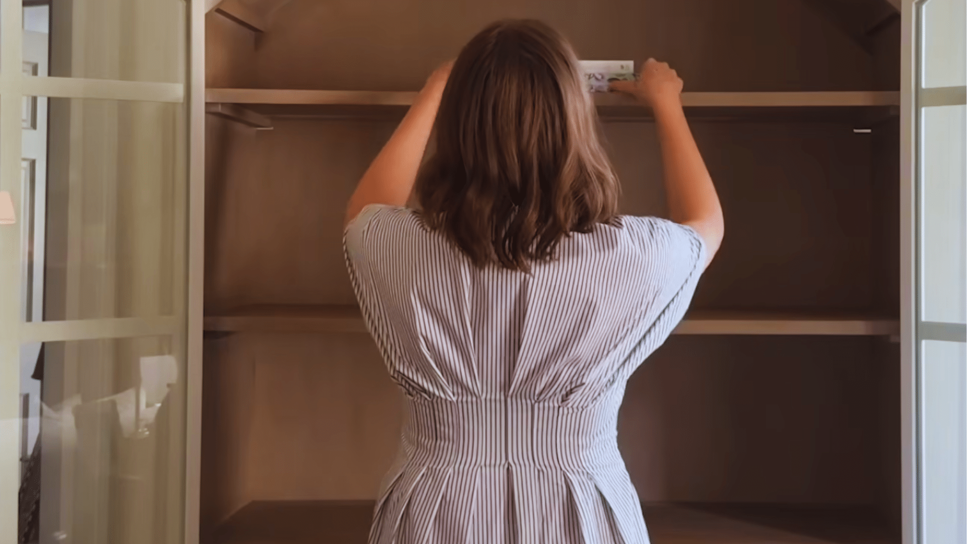 woman arranging books on high shelf to build a strong base with books in a wooden bookshelf