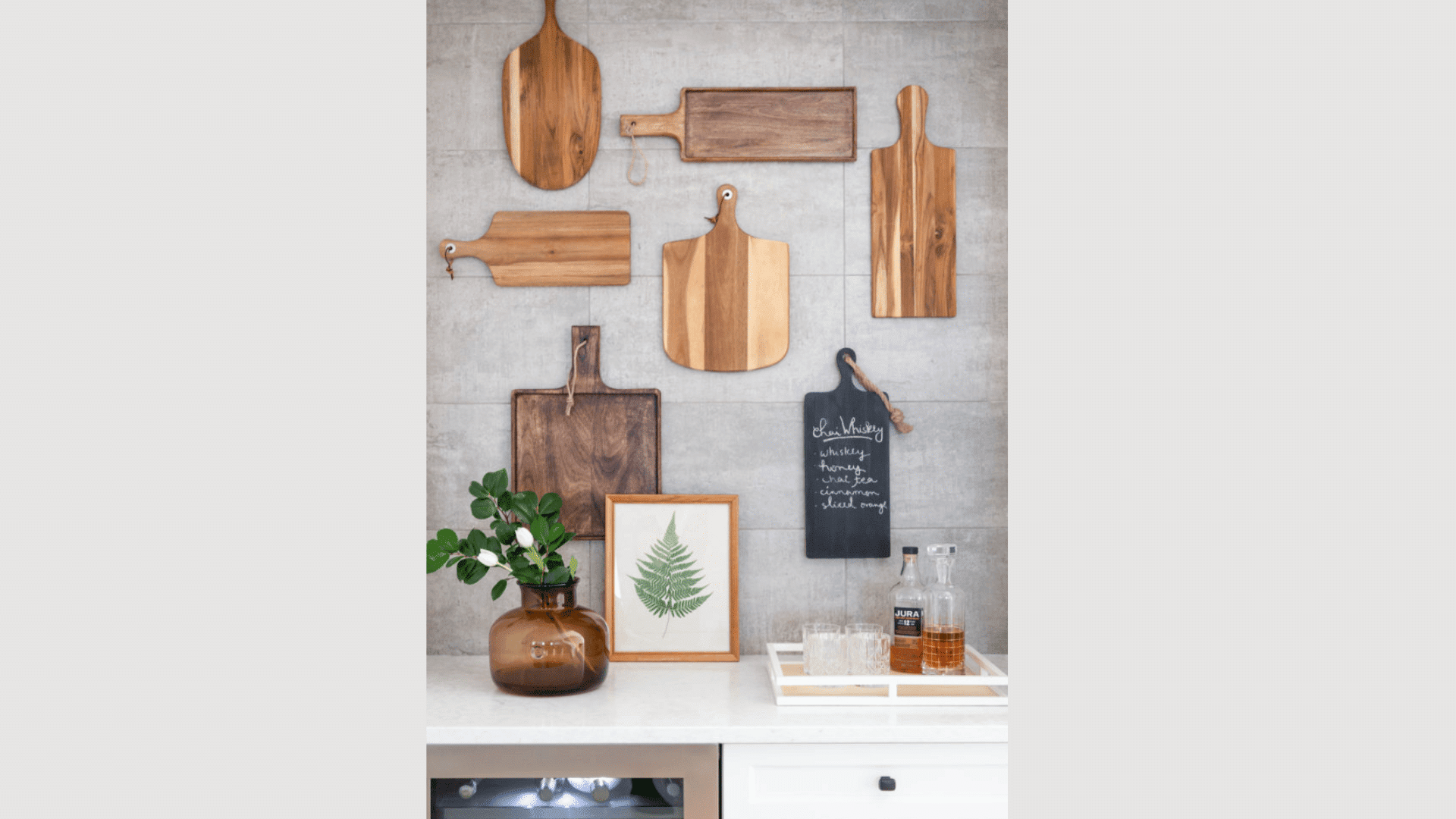 wood cutting boards hanging on kitchen wall above counter with plant and framed leaf art